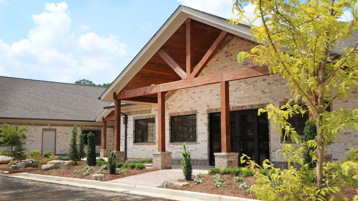 Exterior of brick building with wooden beams and landscaped entry