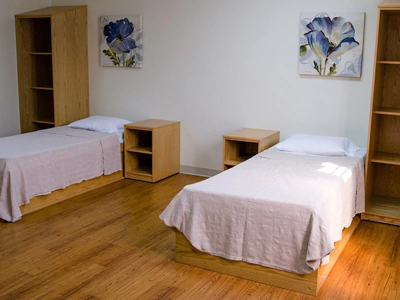 Shared inpatient bedroom with two beds and wooden furniture
