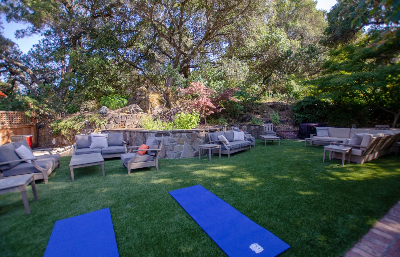 Grassy backyard with outdoor seating and yoga mats.