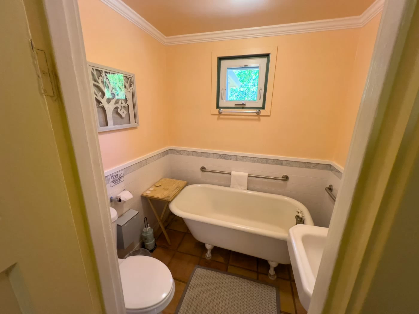 Bathroom with clawfoot tub, toilet, and small window