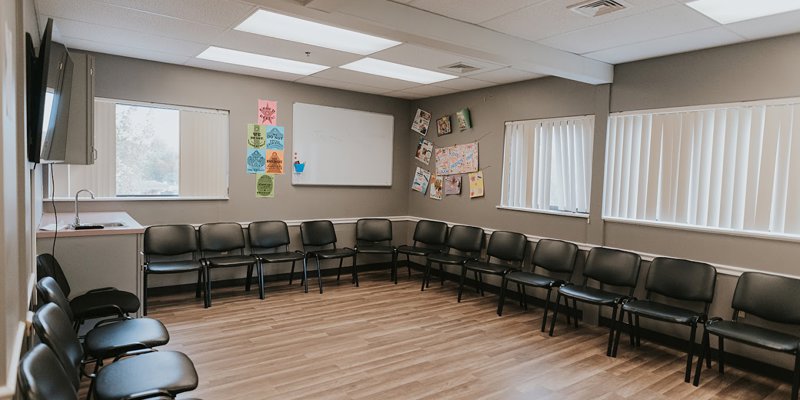 A spacious and well-lit room with chairs arranged in a circle, perfect for group meetings or therapy sessions, with inspiring posters on the walls.