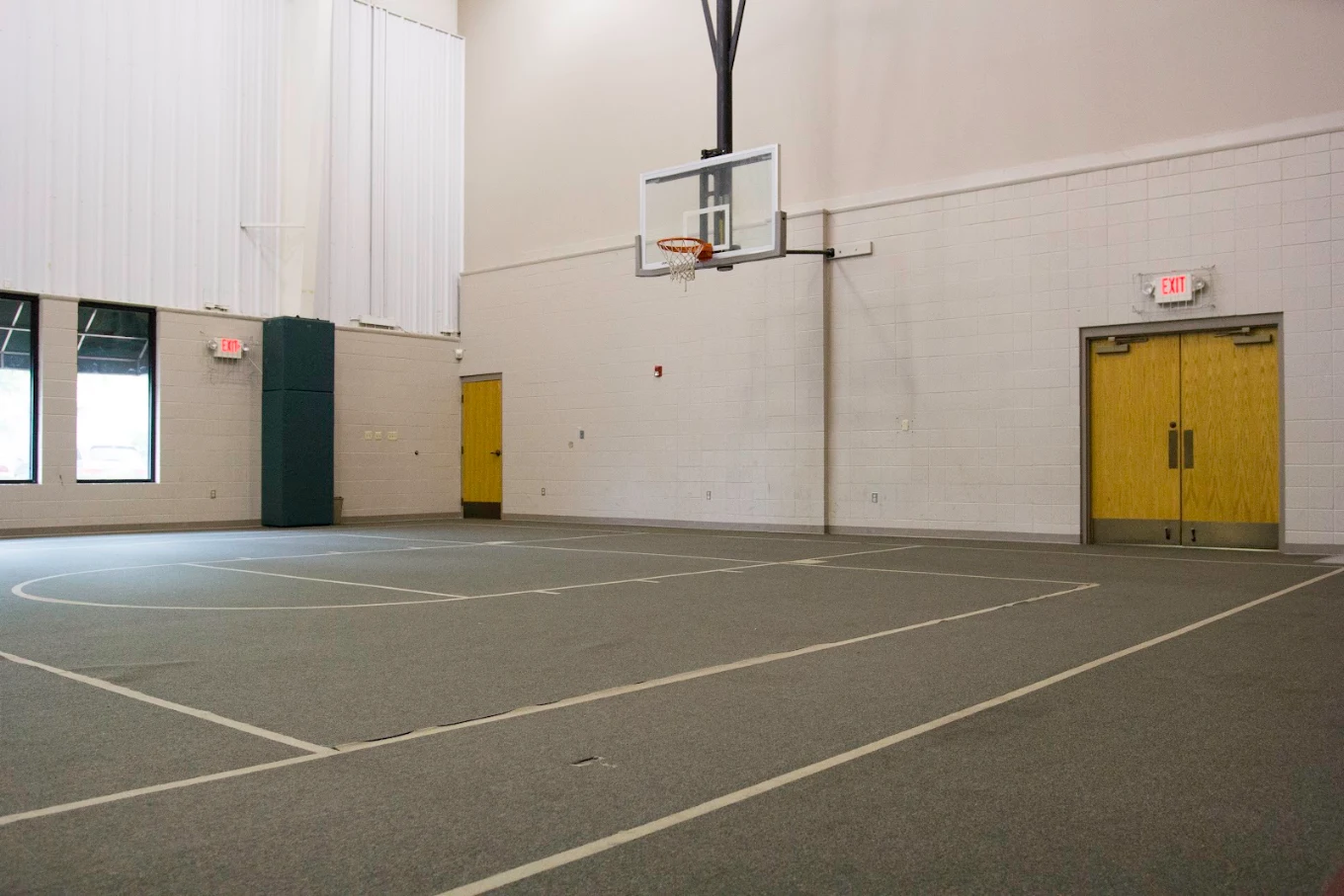 Indoor basketball court with hoop and marked court lines.