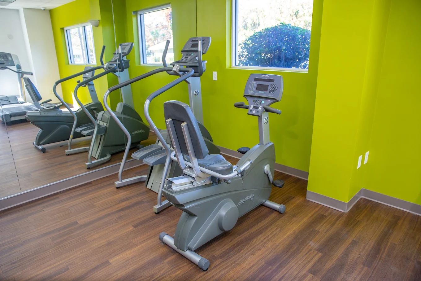 Fitness room with cardio machines, mirrors, and large windows