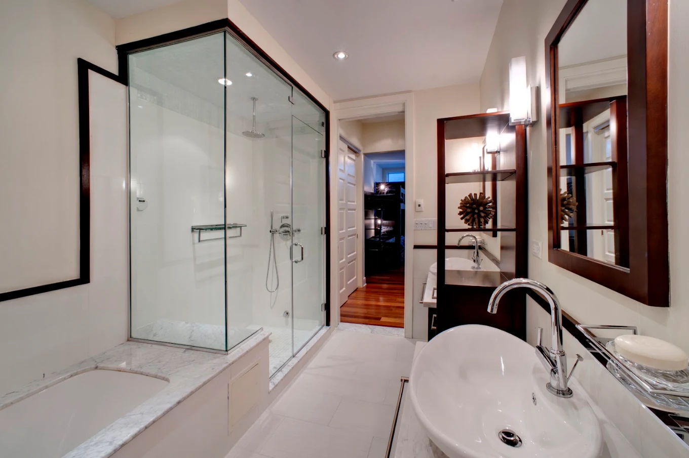 Modern bathroom with glass-enclosed shower, bathtub, vessel sink, mirrors, and wood accents