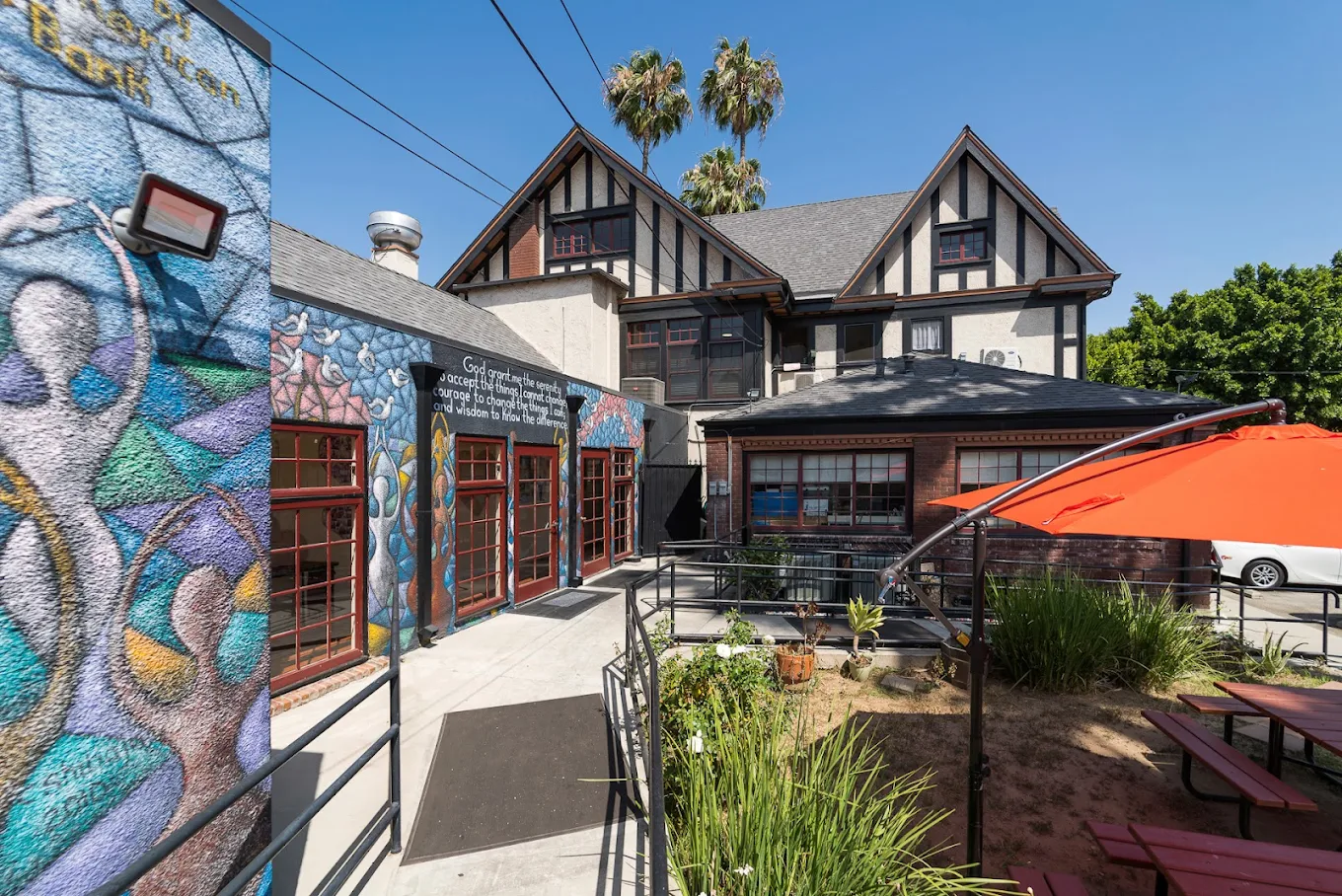 Colorful mural on rehab center with red-trimmed windows and sloped ramp