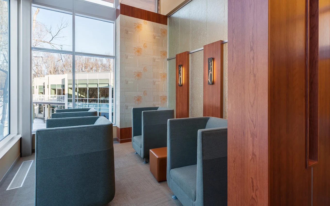Quiet seating area with high-backed chairs beside floor-to-ceiling windows