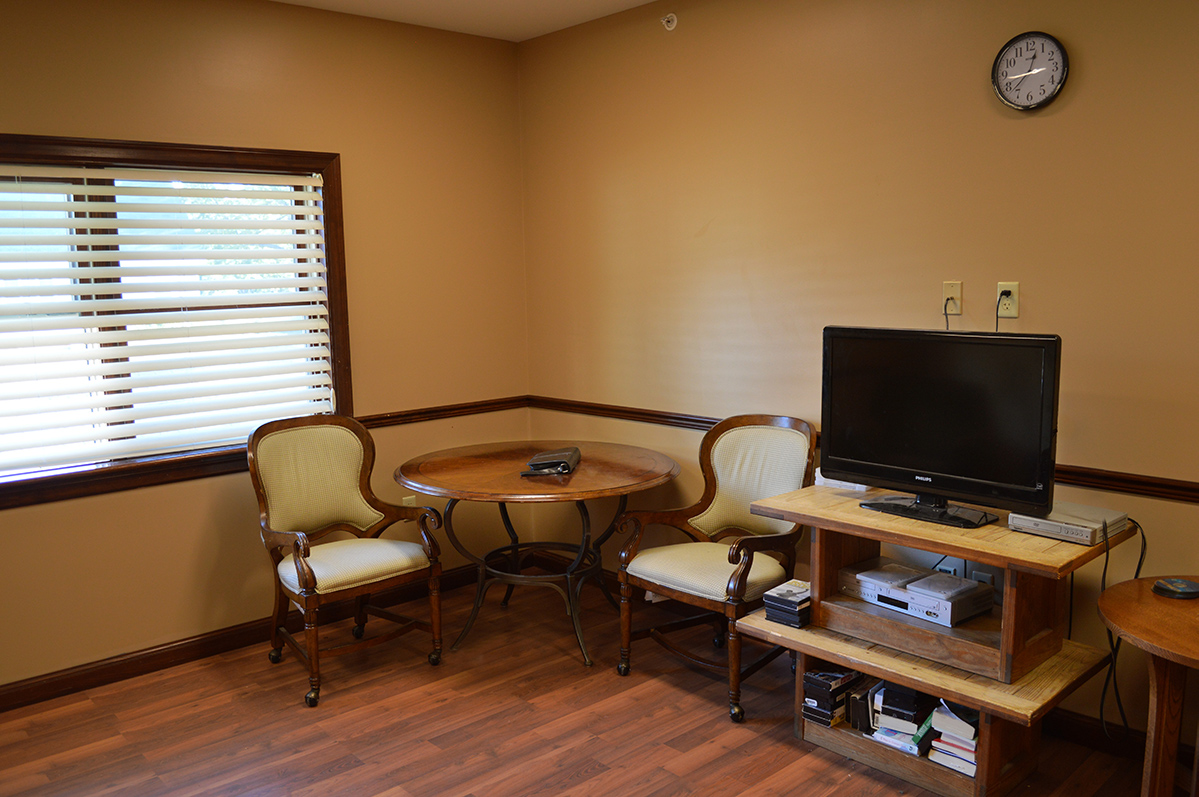 Lounge with TV, chairs, and small round table near window