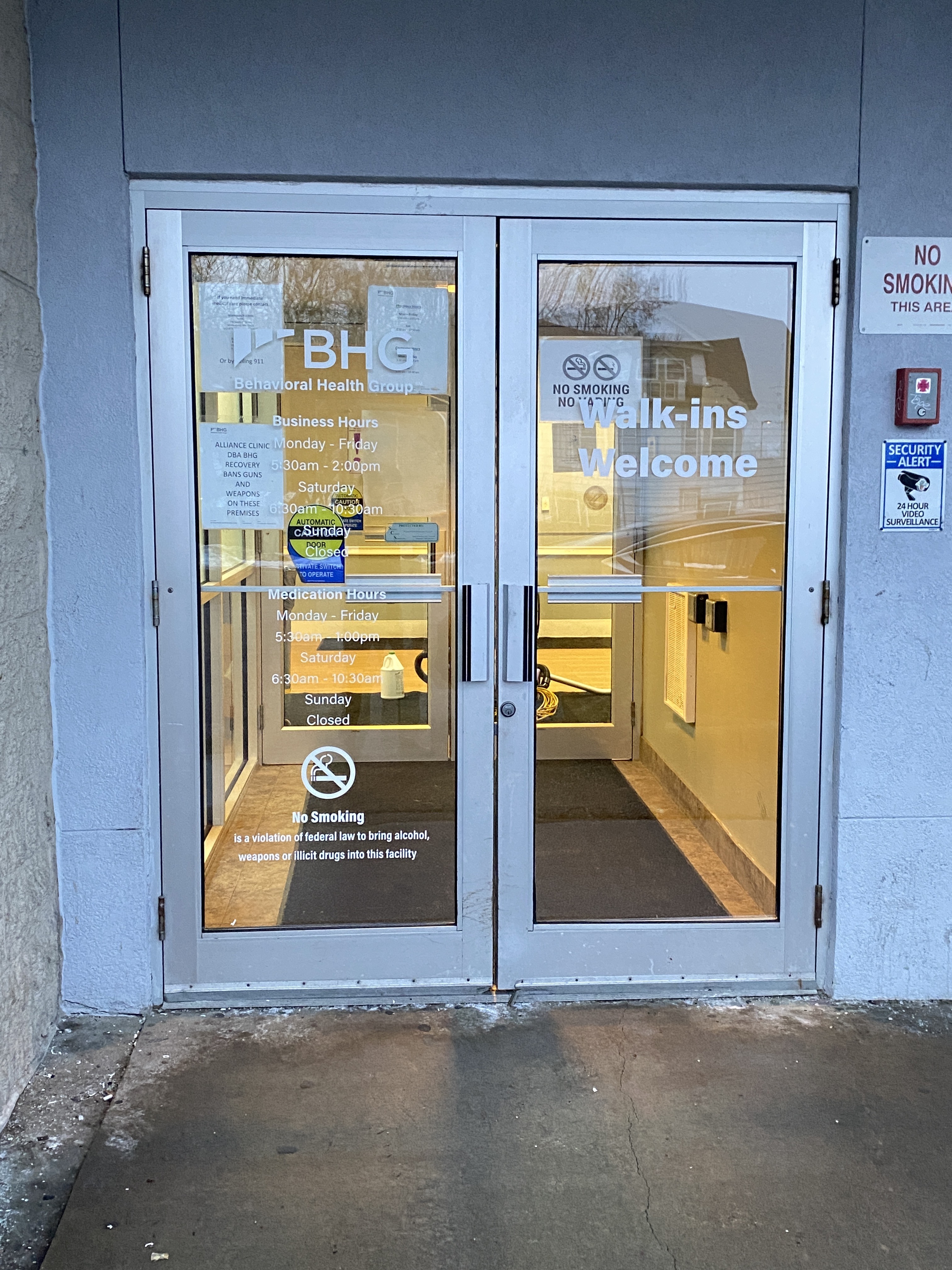 Glass entrance doors with business hours and welcome sign