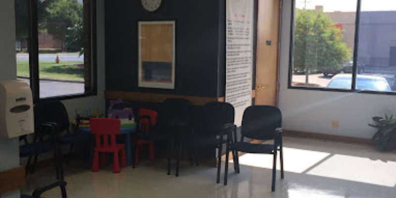 A bright and welcoming waiting area with comfortable chairs, large windows, and a children's play area. The space feels open and calming.