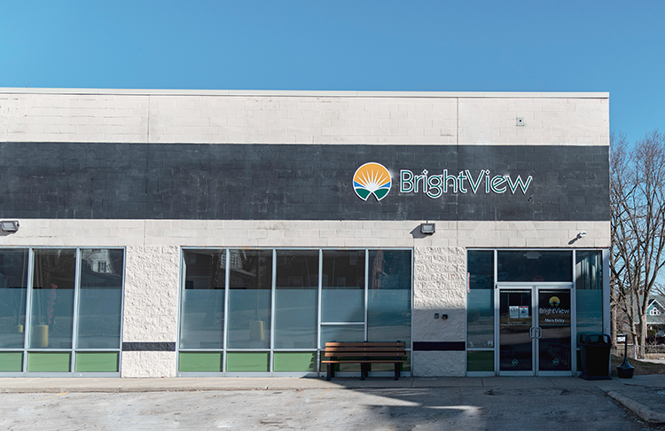 Front exterior of BrightView Health Mansfield with the BrightView logo above the entrance, large windows, a bench, and white and dark gray facade