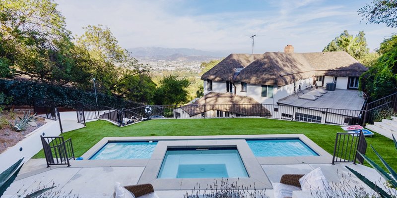 Sparkling outdoor pool and spa nestled in a scenic backyard with lush greenery and panoramic mountain views, creating a peaceful retreat.