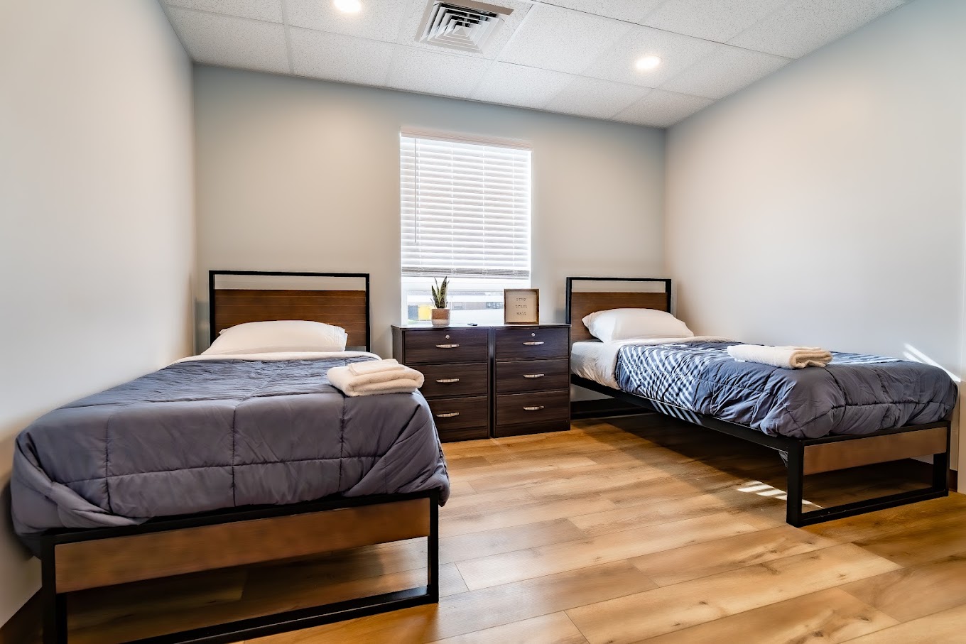 Two twin beds, striped bedding, nightstands, and wall tapestry.