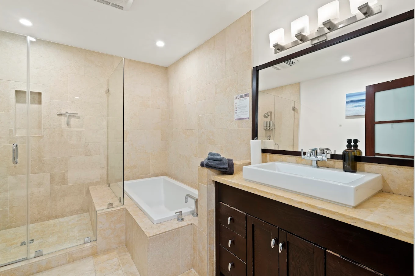 Walk-in shower and bathtub with stone tile and wide vanity