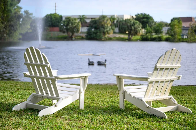 Lake with fountain and chairs on grassy shore