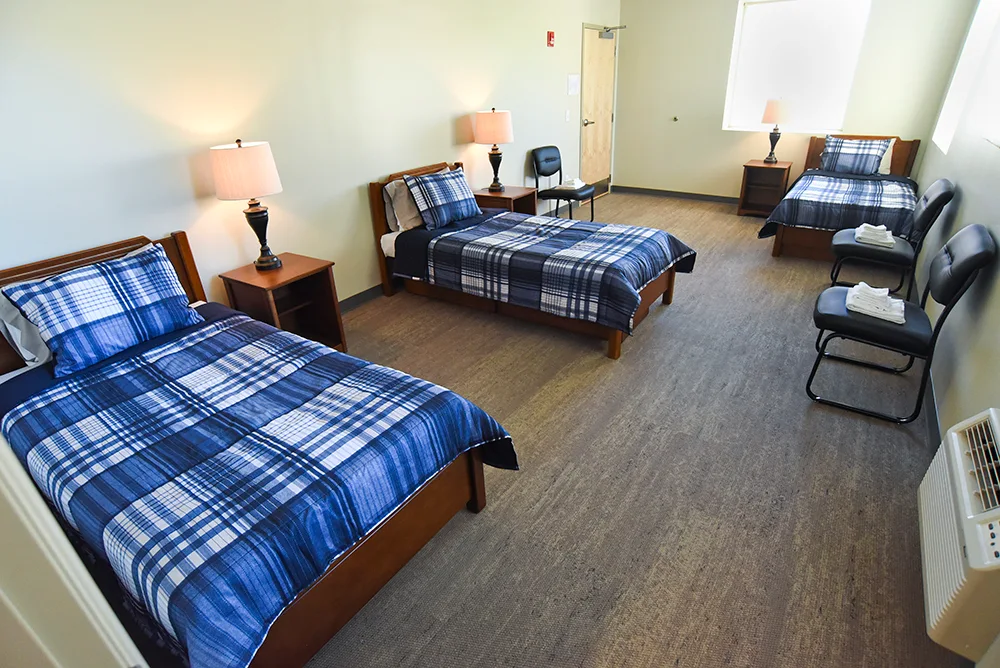 Spacious bedroom with twin beds, plaid bedding, and chairs