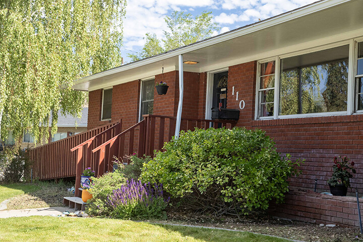 Red brick residential building with wooden steps and shrubs