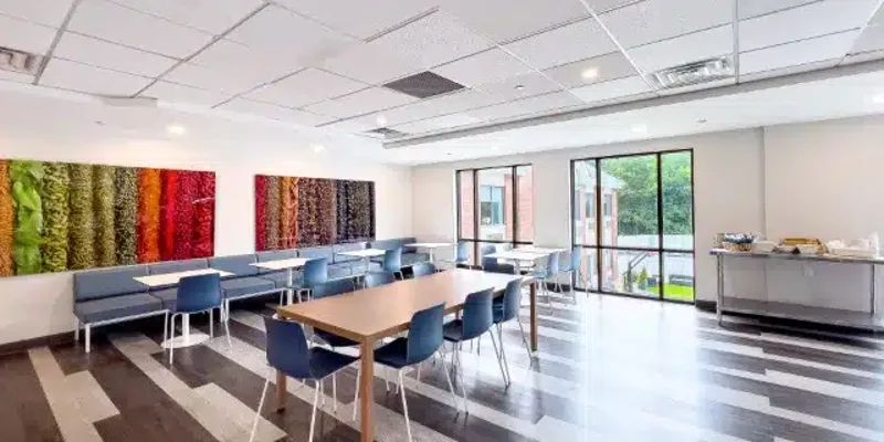  Bright, modern dining area with vibrant wall art, large windows, and ample seating, offering a welcoming space for meals and socializing.