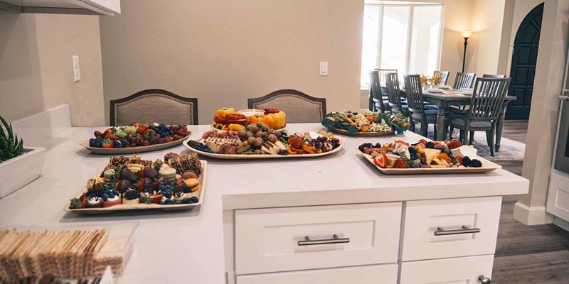 A bright and inviting kitchen setup with an array of colorful, fresh fruit and appetizers elegantly displayed on the countertop.