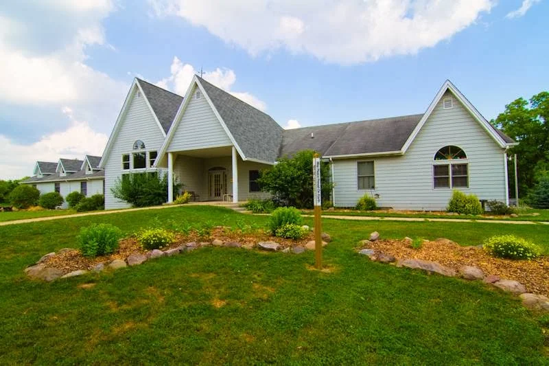 White residential building with lawn and landscaped gardens