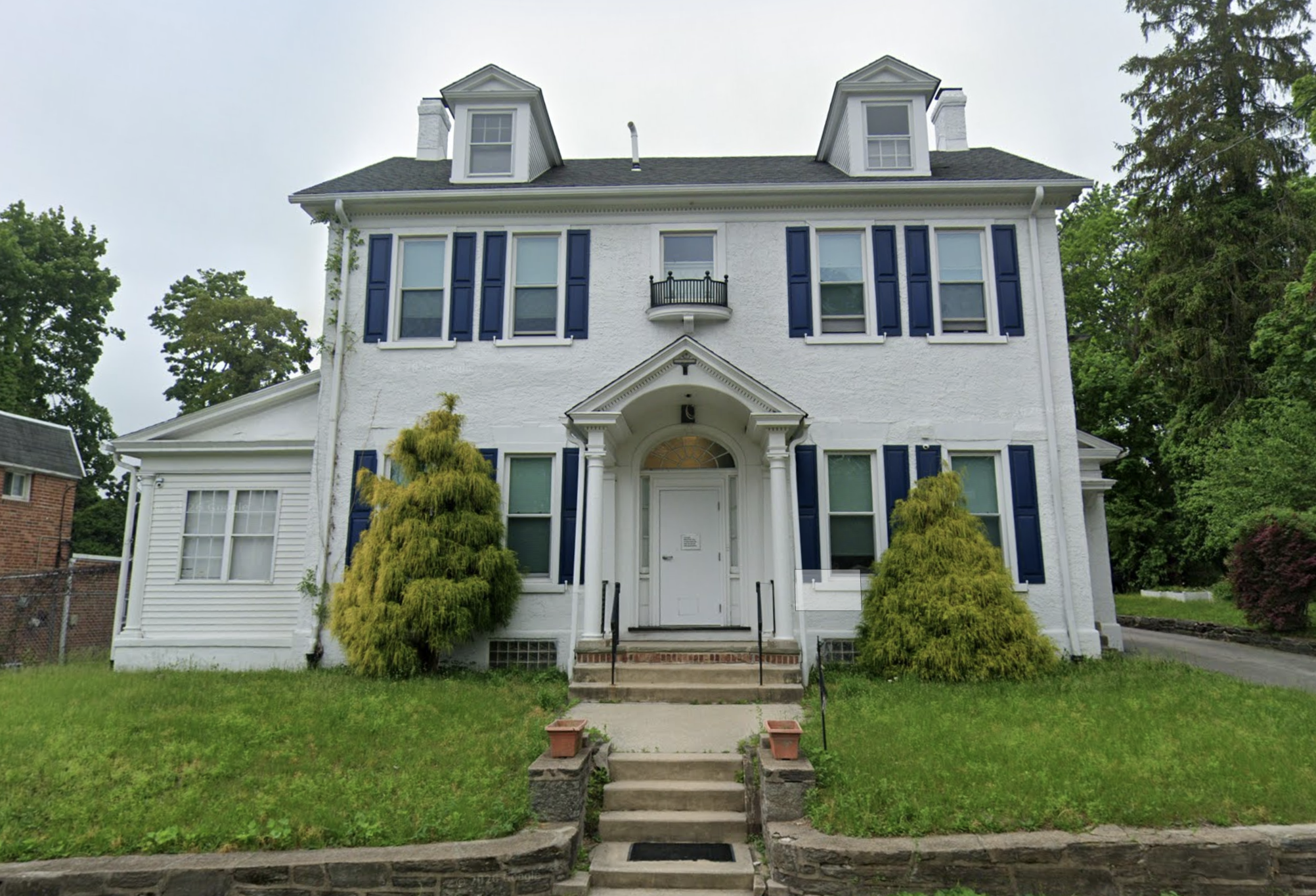 Three-story white building with blue shutters and front steps