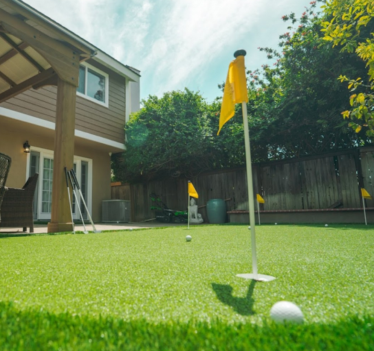 Backyard putting green with golf flags and shaded seating area