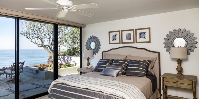 Cozy bedroom with ocean views, stylish décor, and a neutral color palette. Large windows offer serene scenery and natural light.