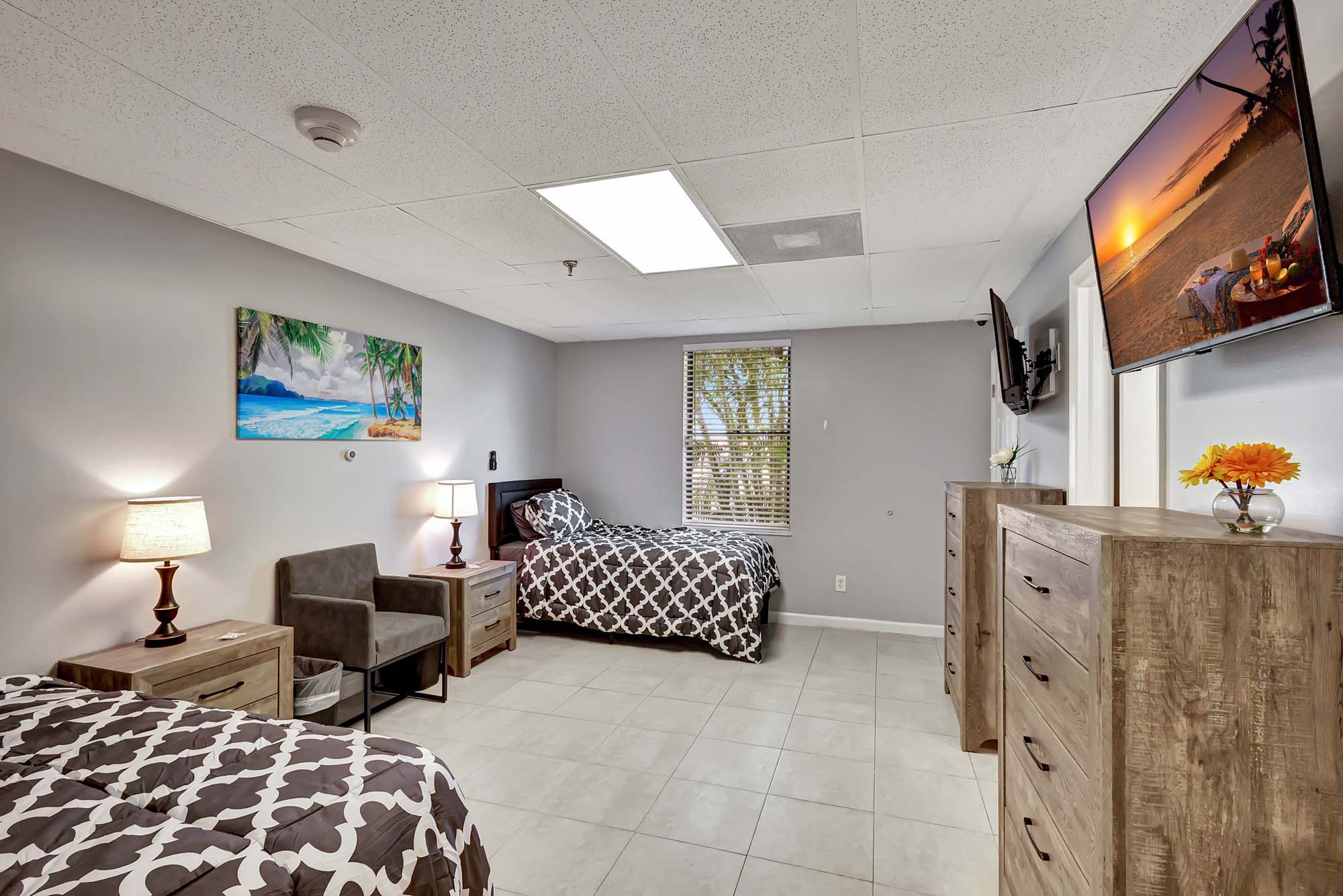 Bedroom with two beds, dressers, and wall-mounted TV