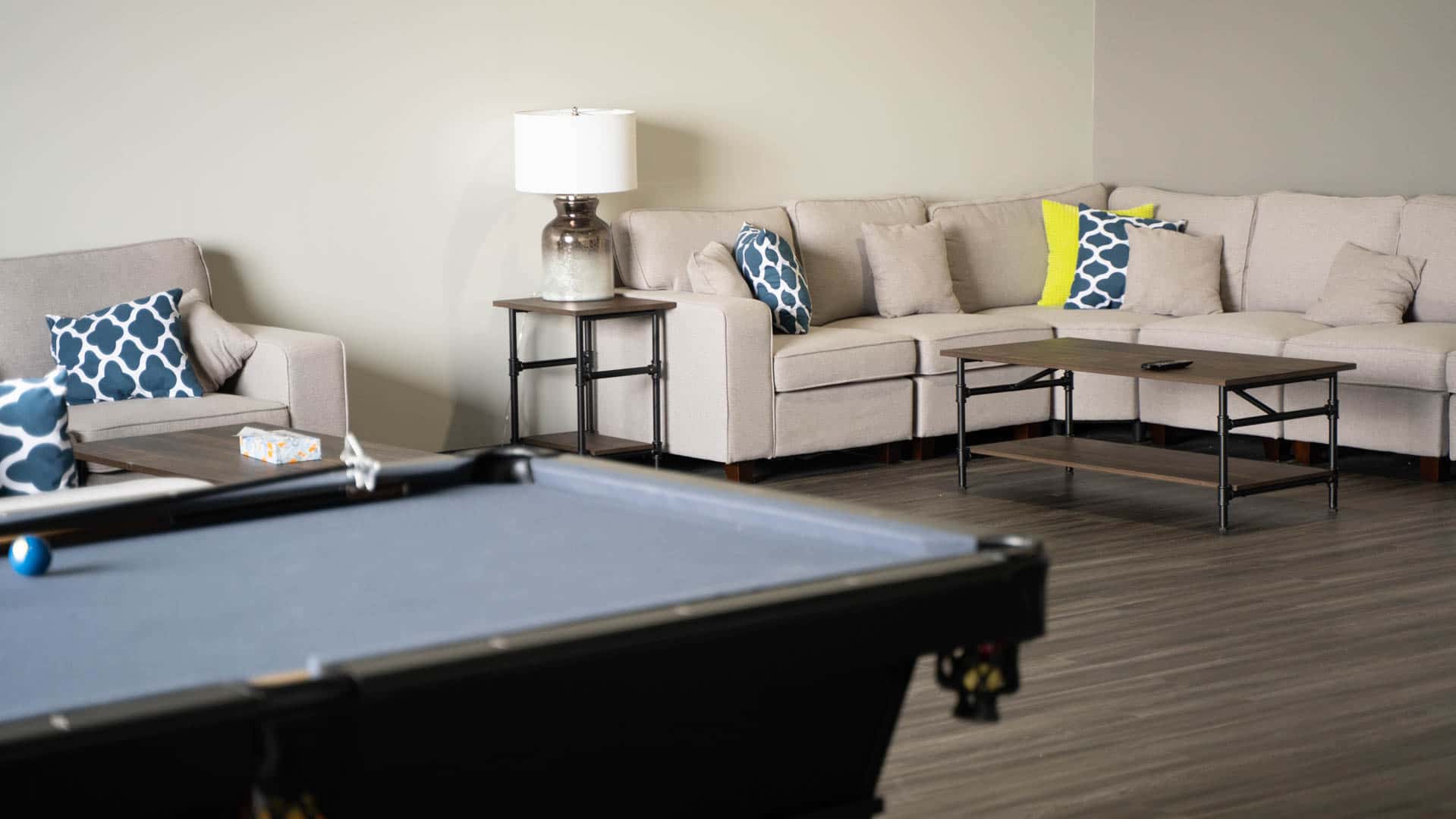 A cozy beige sectional couch with blue and yellow pillows in a lounge area.