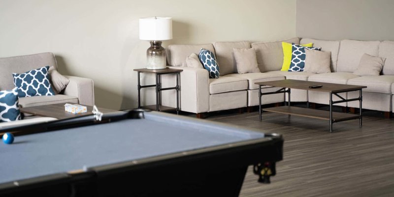 Comfortable lounge area with a cozy sectional sofa, colorful pillows, a coffee table, and a pool table, perfect for relaxation and socializing.