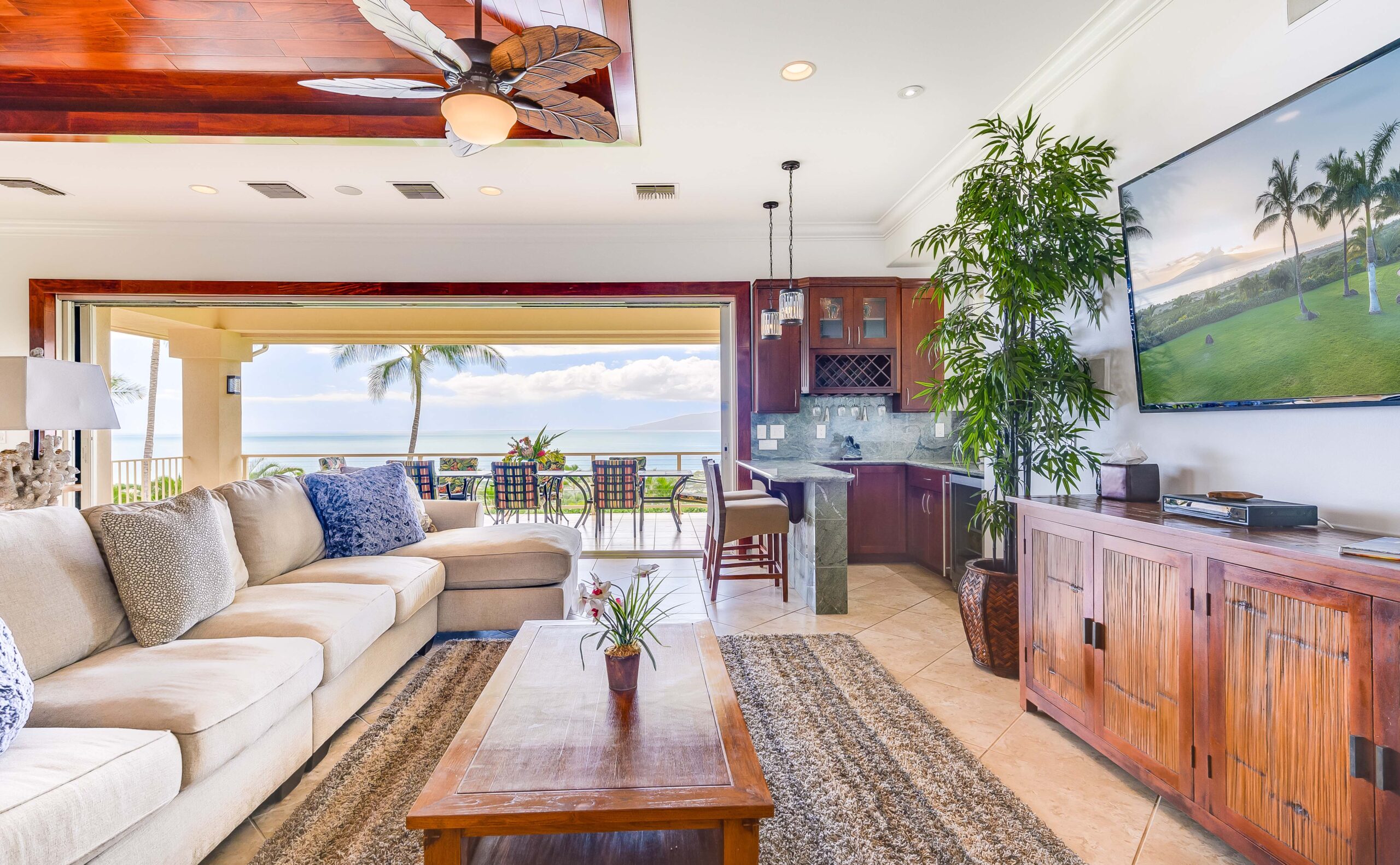 Comfortable living room with kitchenette opening onto a covered lanai overlooking the ocean
