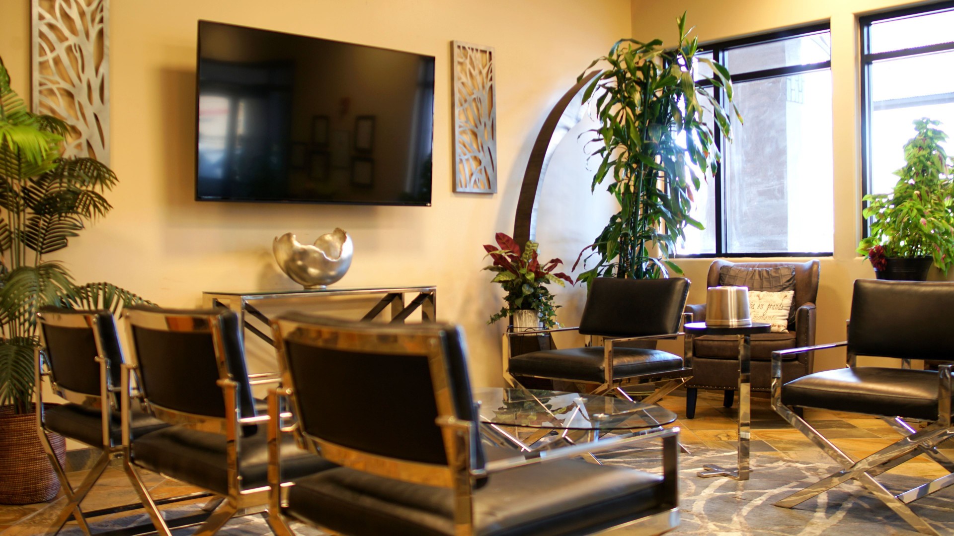 Lounge with chairs, plants, and a large TV.