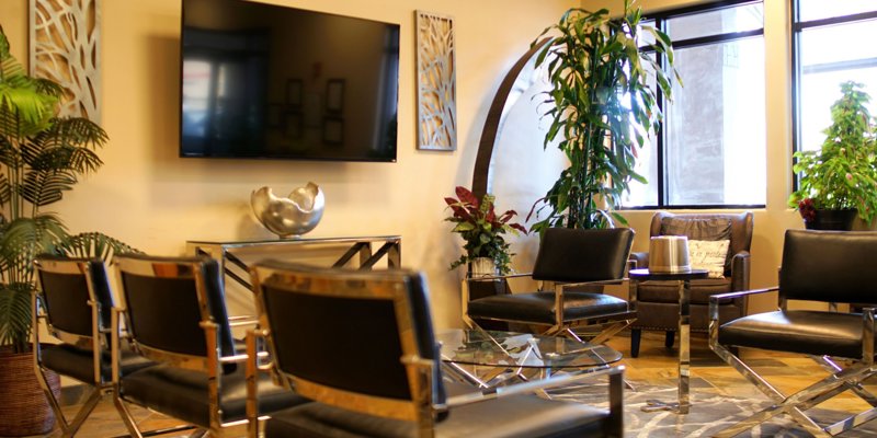  A stylish and inviting lounge with modern chairs, vibrant plants, and a large TV, offering a comfortable space for relaxation and socializing.