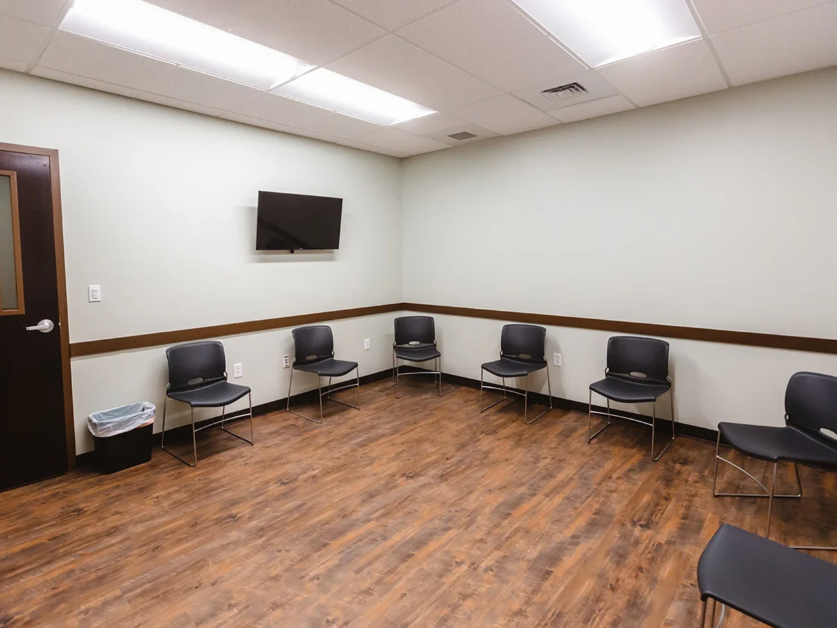 Chairs arranged in a circle inside a small therapy room with wall-mounted TV