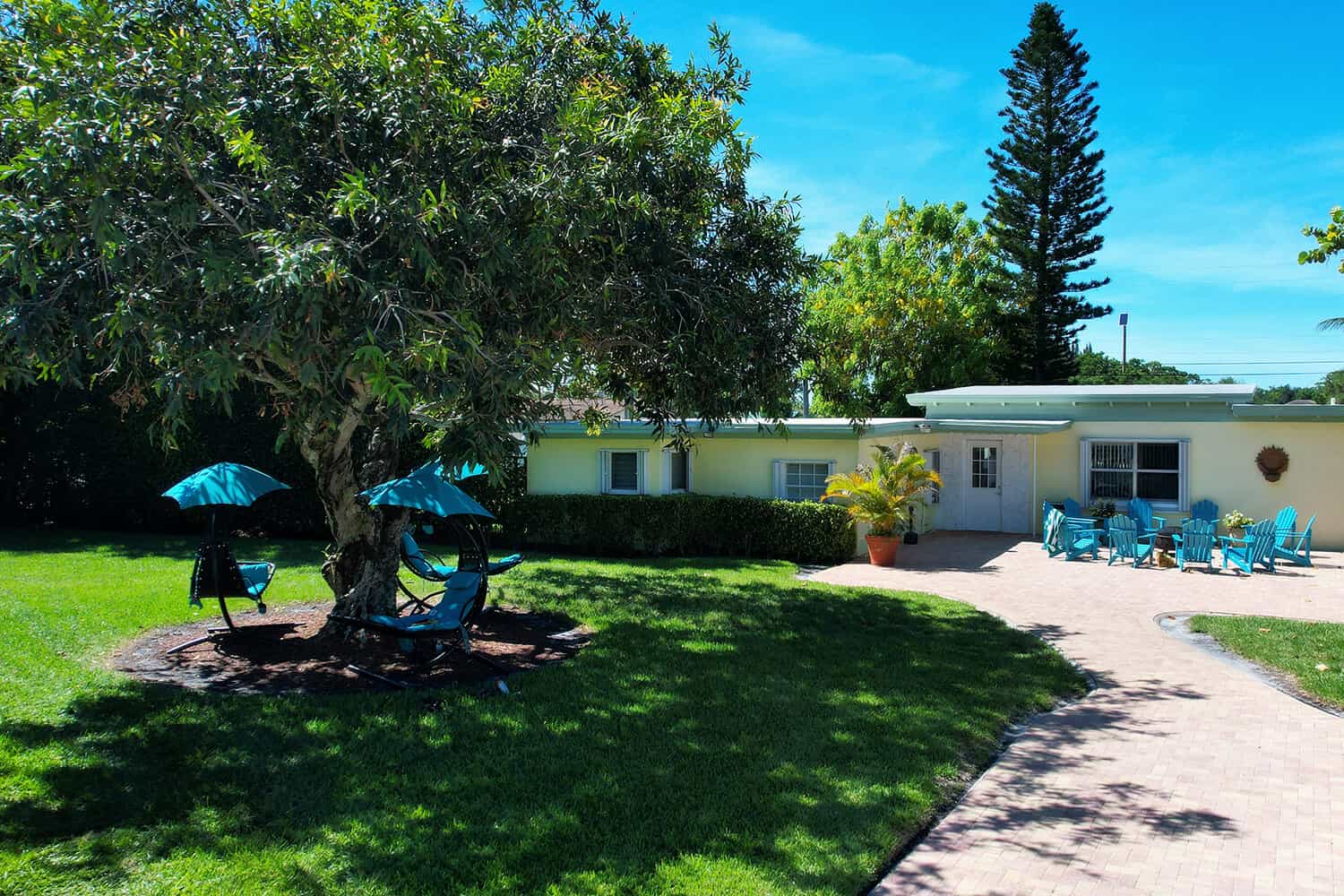  Outdoor seating area with shaded lounge chairs and greenery.