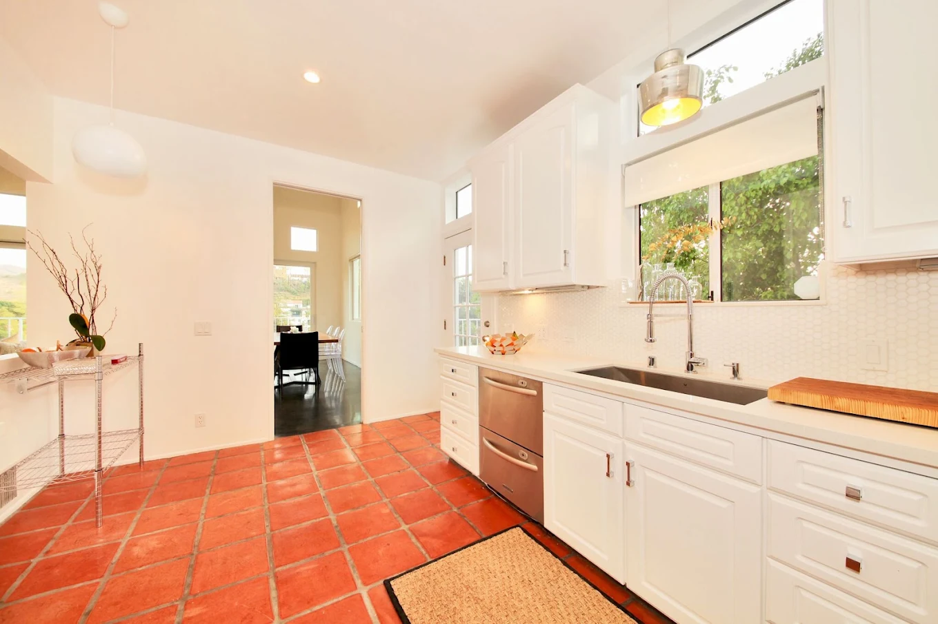 Modern kitchen with white cabinetry, stainless steel appliances, and terracotta tile floor in Los Angeles rehab facility