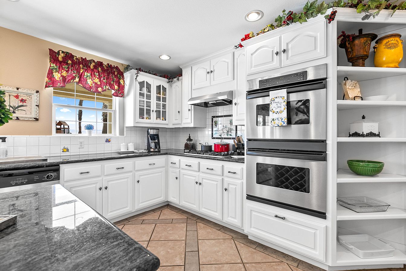 White kitchen with modern appliances and window view