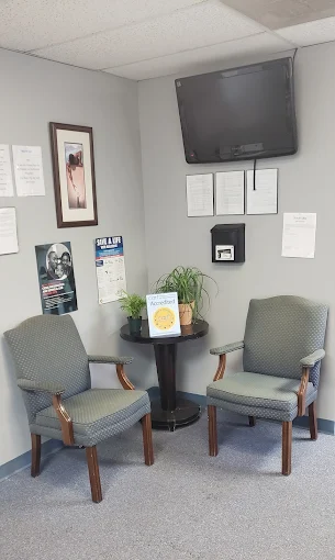 Small waiting area with two chairs, a table, and a wall-mounted TV.
