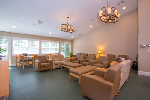 A lounge area with cushioned chairs, tables, and warm lighting.