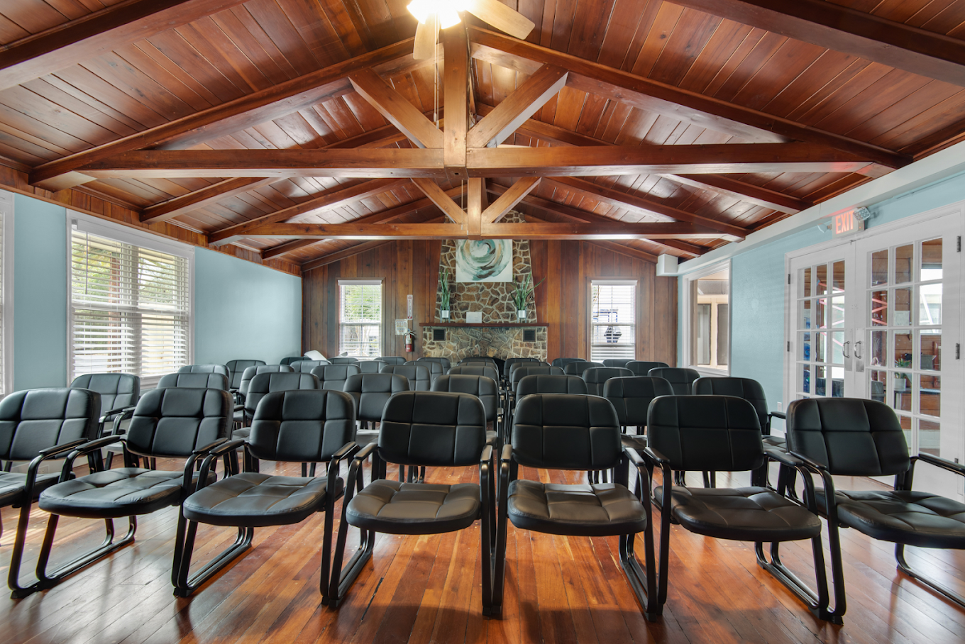 roup room with rows of chairs, wood ceiling, and fireplace
