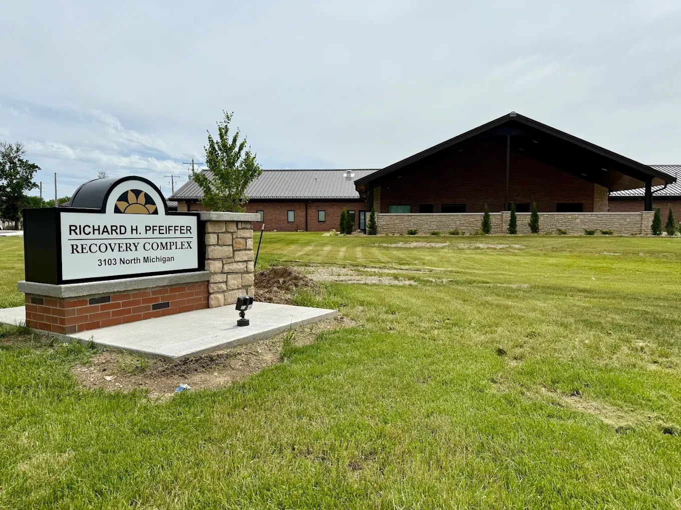 Entrance sign with building in background on open lawn