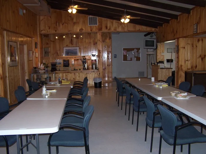 Rustic communal dining area with long tables and wood-paneled walls