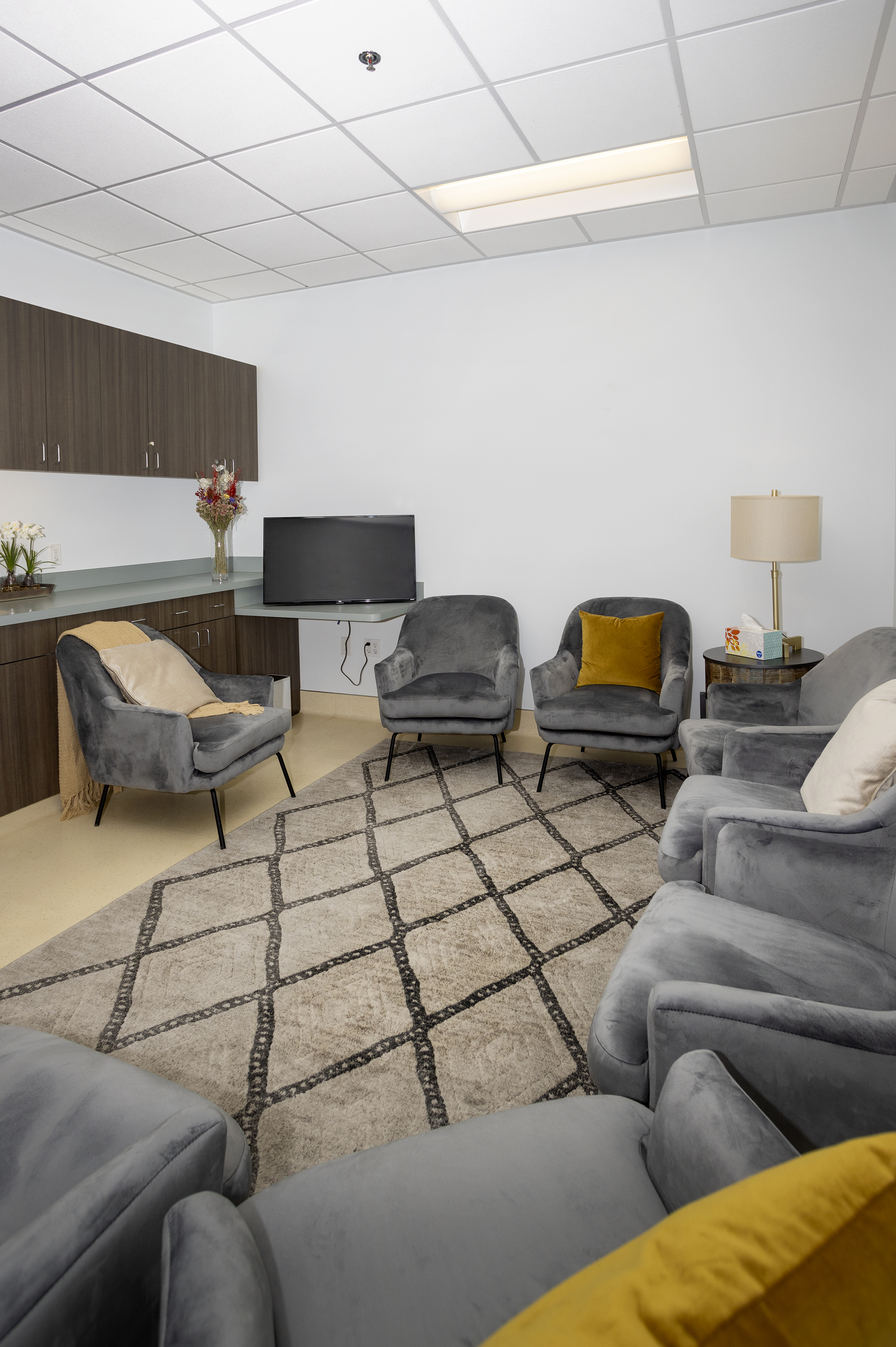 Cozy group room with gray chairs and wall-mounted TV