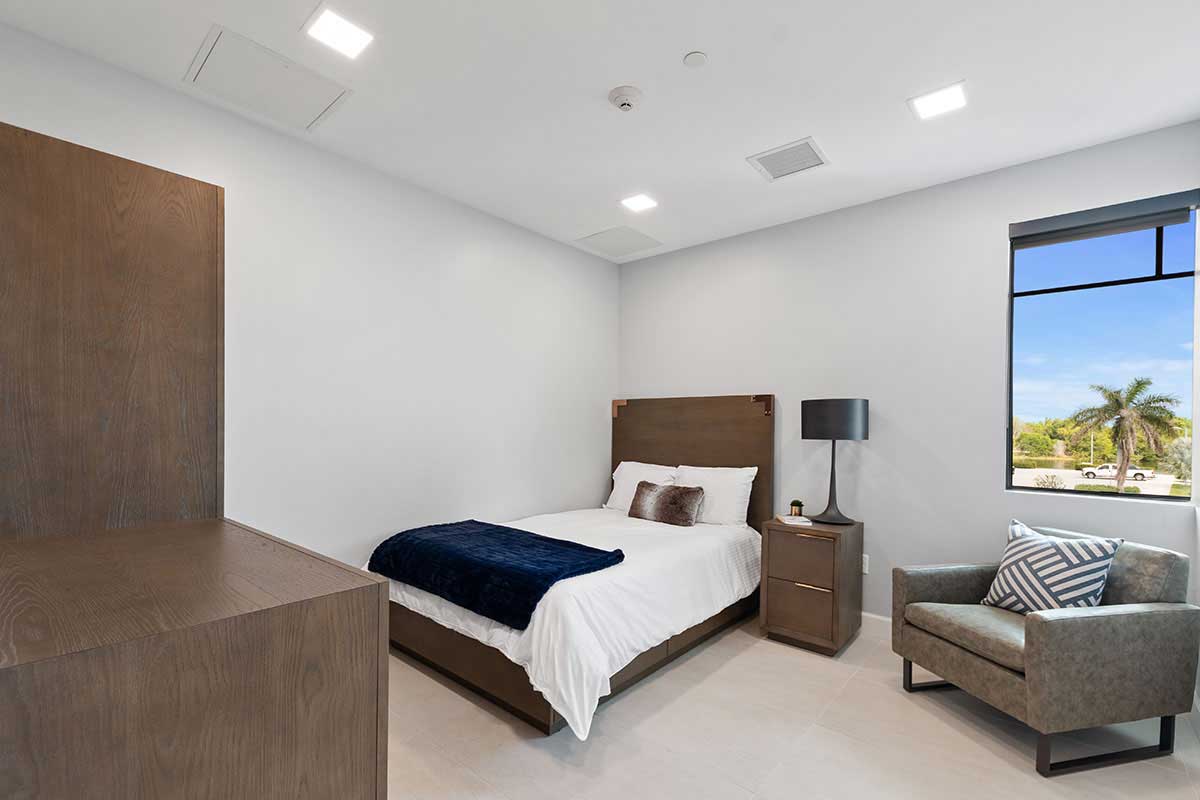 Single bed client room with desk and lounge chair