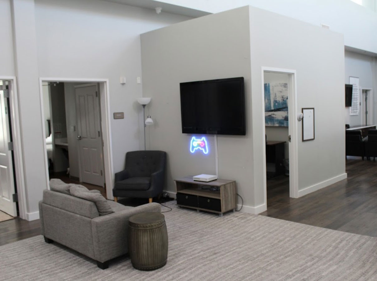  Game area with  seating, and a neon game controller sign,