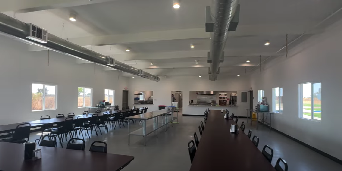 Spacious cafeteria with long tables and serving area