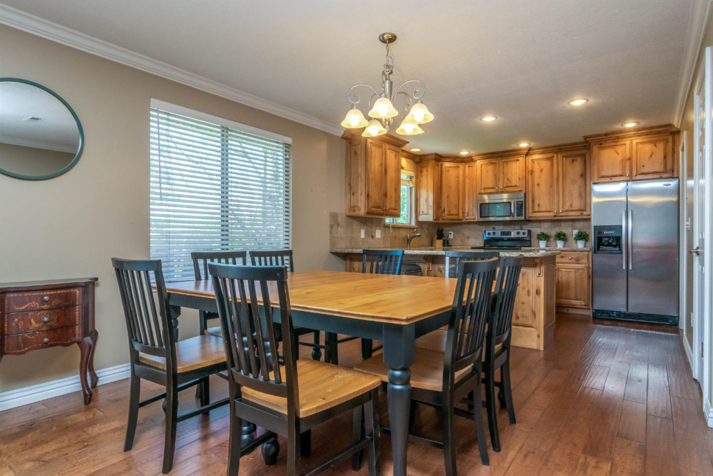 Dining area with wooden table beside bright kitchen