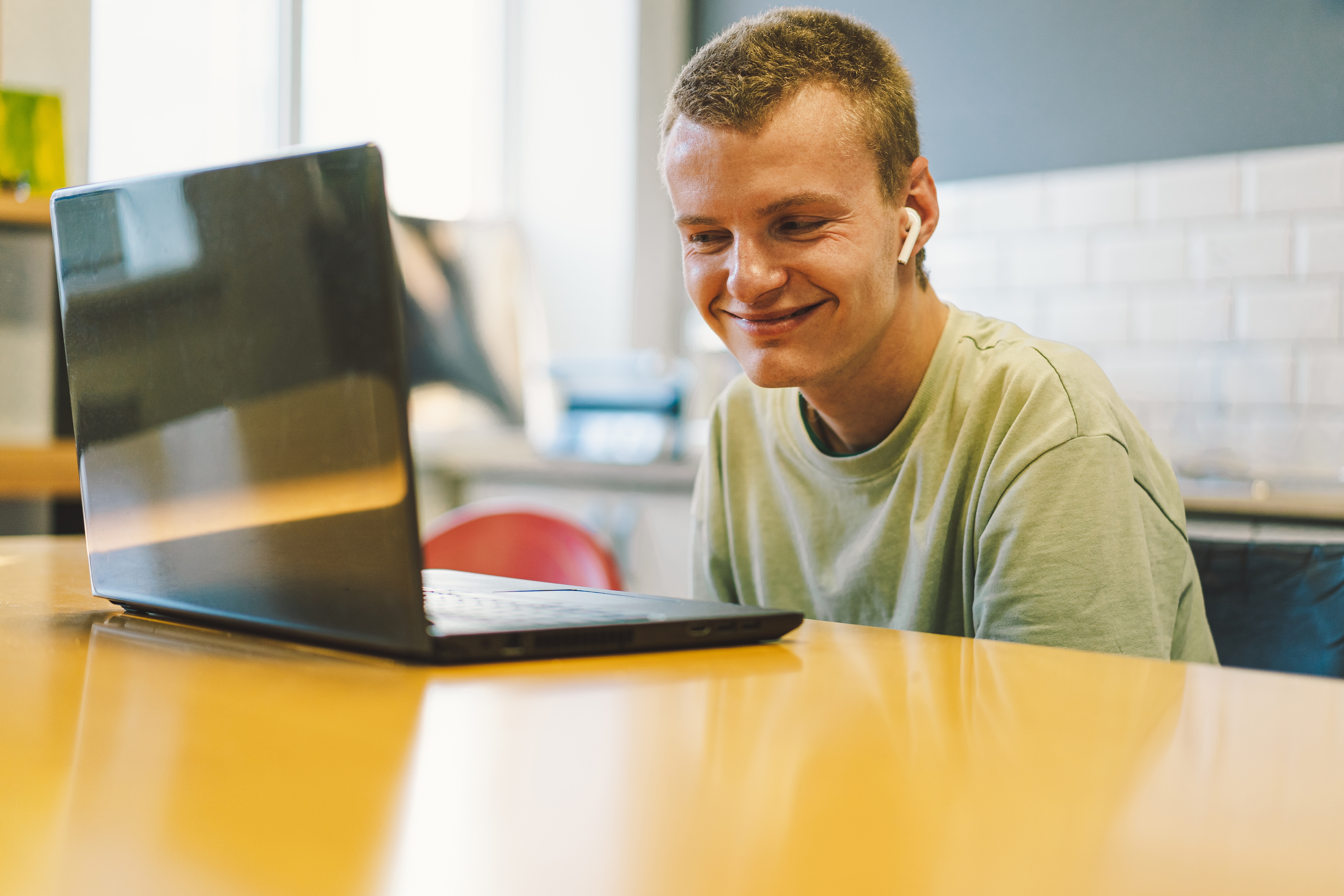 Teen boy smiling while working on a laptop.