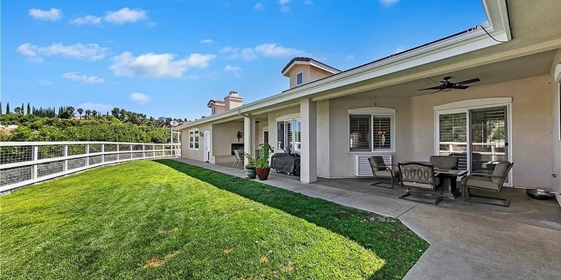 Spacious backyard patio featuring comfortable seating, lush green lawn, and scenic views, perfect for relaxation and outdoor dining.