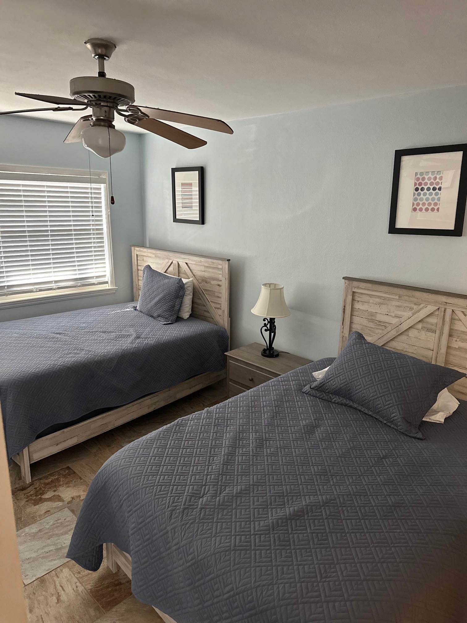 Twin beds with blue quilts and ceiling fan