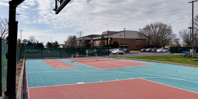  A well-maintained outdoor sports court featuring basketball and shuffleboard, ideal for recreational activities and promoting wellness.